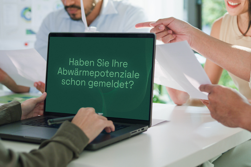 Besprechungssituation mit mehreren Menschen mit Laptop und der Frage: Haben Sie Abwärmepotentiale schon gemeldet?