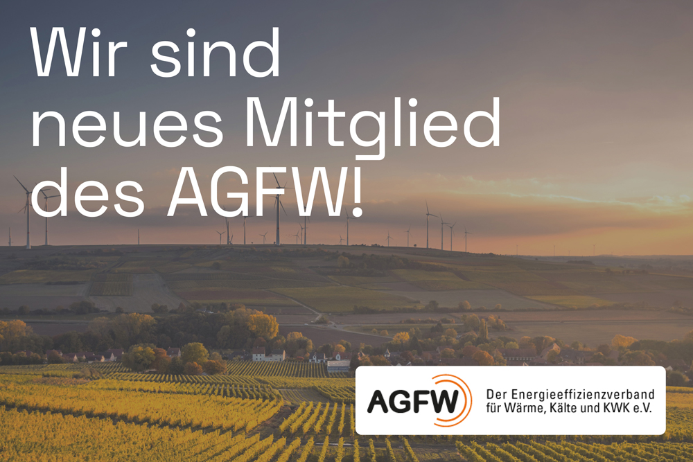 Luftaufnahme einer Landschaft mit Windrädern im Hintergrund. Darauf der Text "Wir sind neues Mitglied des AGFW" und das AGFW-Logo in der rechten unteren Ecke mit dem Text "AGFW, dem Energieeffizienzverband für Wärme, Kälte und KWK e.V."